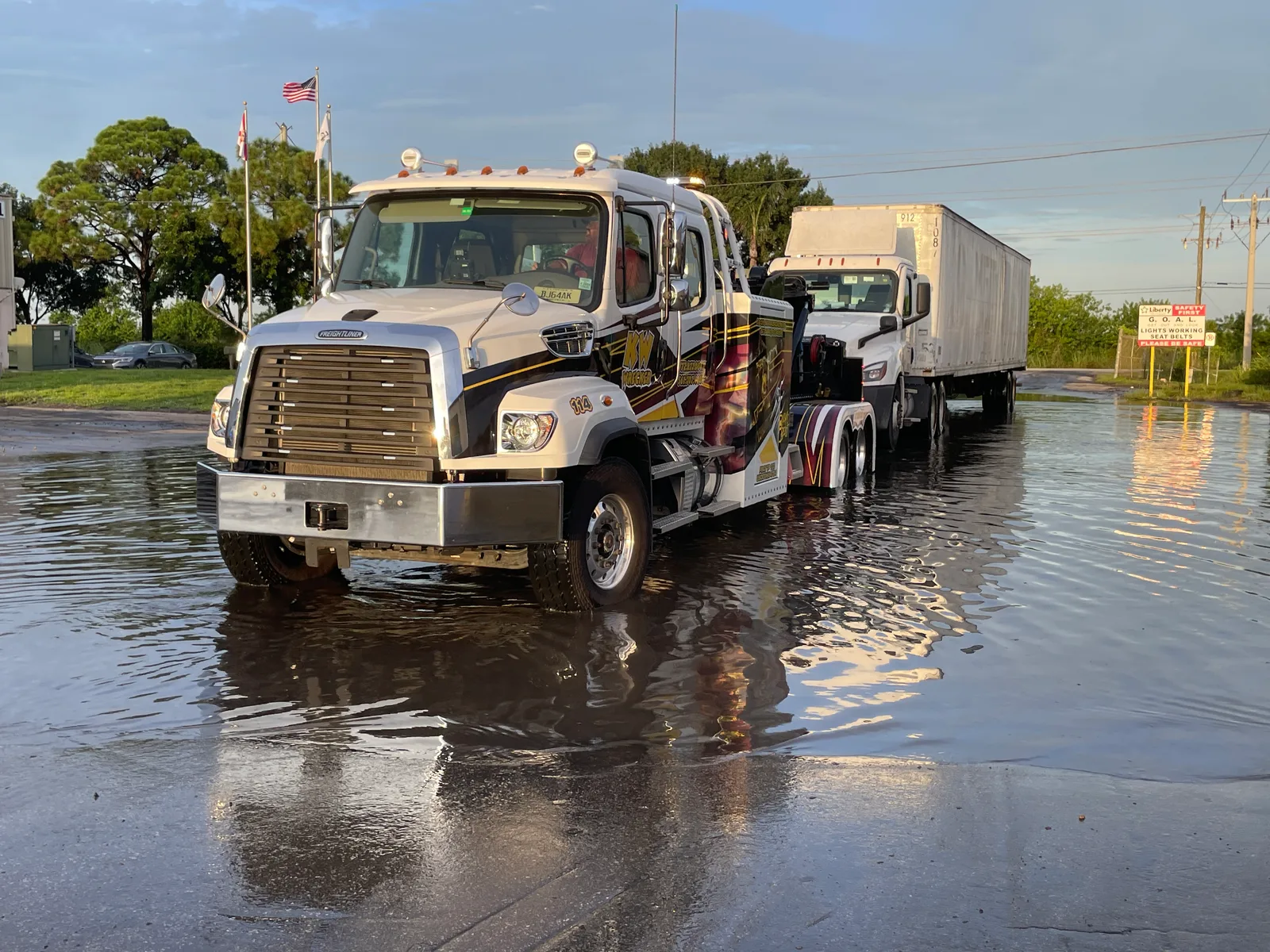KW Wrecker Service Freightliner wrecker towing a semi-trailer through a flooded South Florida roadway