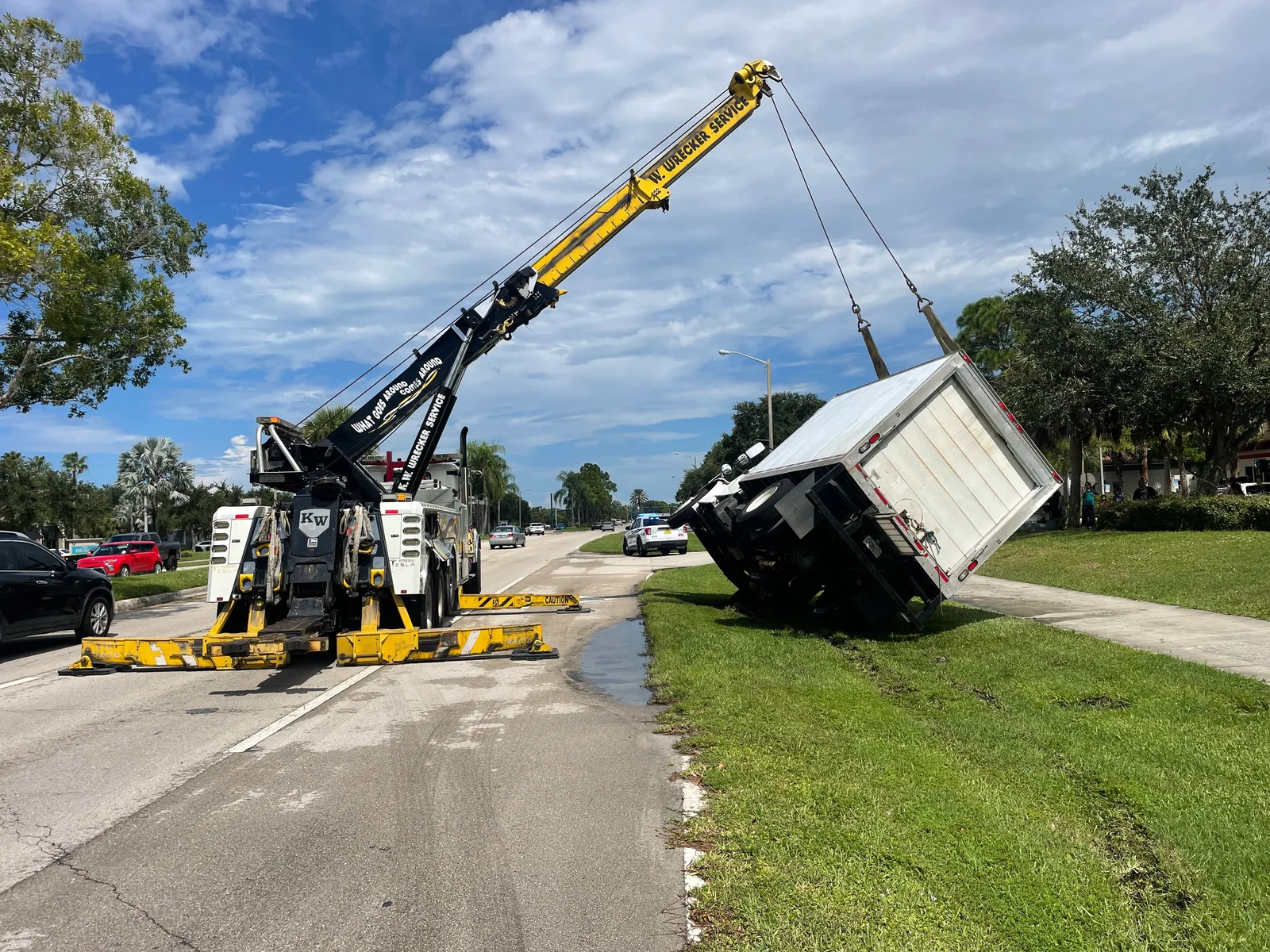KW Wrecker Service heavy rotator recovering an overturned box truck from a roadside ditch